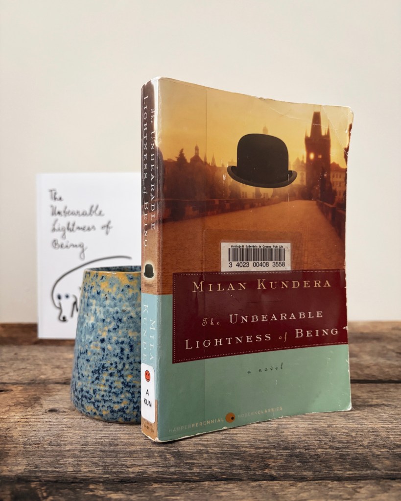 Two different cover editions of the novel The Unbearable Lightness of Being by Milan Kundera, with the library book copy sharply in focus.